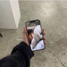 someone holding up their cell phone with the screen showing an image of a man and his dog