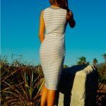 a woman in a white dress is standing on a rock and looking into the distance