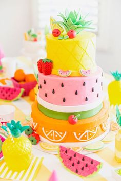 a multi layer cake with pineapples and watermelon on top