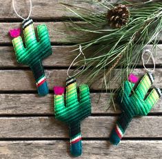 three small cactus ornaments hanging on a wooden table