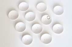 several white bowls are arranged in a pattern on the wall, and one is empty