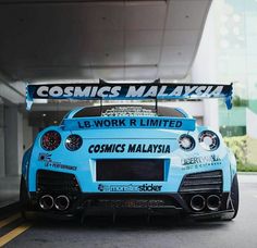 a blue sports car parked in front of a building with a banner on it's side