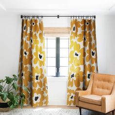 an orange chair sitting in front of a window next to a yellow flowered curtain