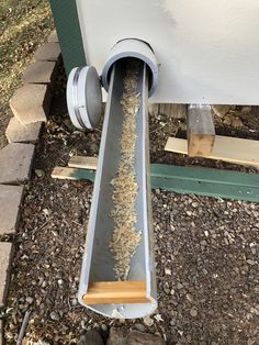 a metal gutter with wood shavings coming out of it