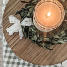 a lit candle sitting on top of a wooden table next to leaves and an angel ornament