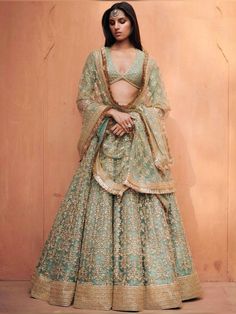 a woman in a green and gold lehenga