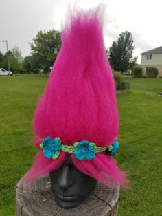 a pink hat with blue flowers on it sitting on top of a wooden tree stump