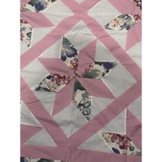 a pink and white quilt with floral designs on it's sides, in the shape of a star