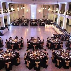 a banquet hall with tables and chairs covered in black cloths, decorated with candles