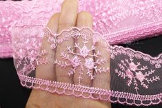 a hand is holding some pink lace