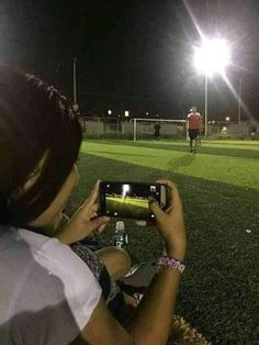 a person taking a photo with a cell phone at night on a soccer field,