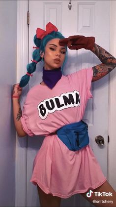 a woman in a pink shirt and blue skirt posing for the camera with her hands on her head