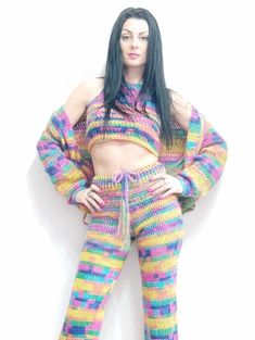 a woman with long black hair is wearing colorful knitted clothing and posing for the camera