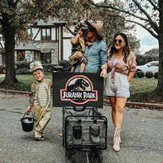 three people and a child are standing in front of a sign that says dinosaur park