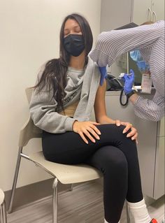 a woman sitting in a chair wearing a mask