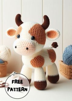 a crocheted cow sitting next to some balls of yarn