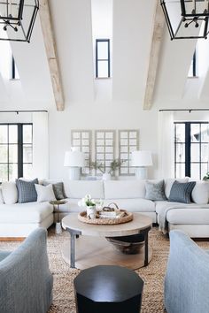 a living room filled with white furniture and lots of windows on top of the ceiling