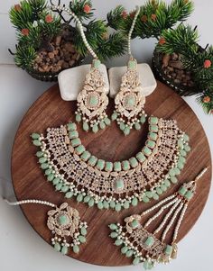 a necklace and earring set on a wooden platter with pine cones in the background