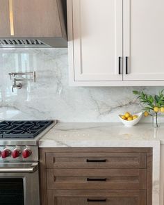 a white kitchen with marble counter tops and wooden cabinetry, along with stainless steel appliances