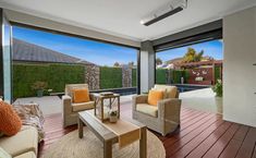 a living room filled with furniture next to a large glass window overlooking a backyard area