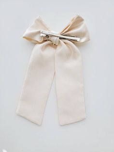 Finish: Alligator Clip * 9 inches long * Material: Satin Elegant Cream Satin Bow, Elegant Cream Bow For Parties, Elegant Cream Bow For Party, Elegant Cream Bow With Ribbon Detail, Elegant Cream Bow With Ribbon, Cream Ribbon Wedding Bow, Cream Satin Bow For Wedding, Bow With Pearls, Beaded Bow