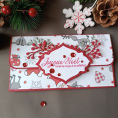 a close up of a christmas card on a table with pine cones and other decorations