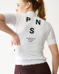 a woman with her back to the camera wearing a white shirt that reads pn s