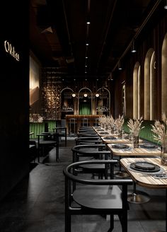 an empty restaurant with long tables and green velvet chairs, in the middle of a dimly lit dining area