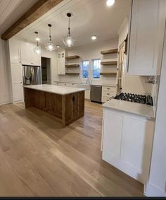 an empty kitchen with wood floors and white cabinets