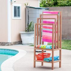 a towel rack next to a pool with towels on it and a red basket in the foreground