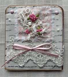 an embroidered piece with pink flowers and lace on it's edge is displayed in front of a white background