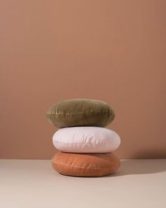 three pillows stacked on top of each other in front of a brown wall and tan floor