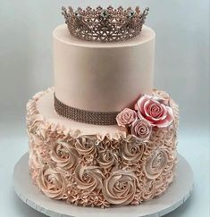 a three tiered cake with roses and a tiara on top that is sitting on a plate