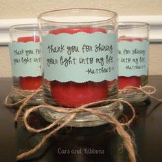 three votive candles with labels on them sitting on a table