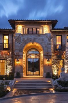 the front entrance to a large home lit up at night