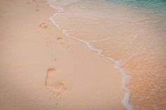 the footprints of two people are in the sand on the beach near the water's edge