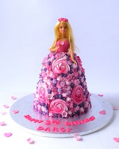 a barbie doll cake with pink and purple flowers on it's tiered skirt