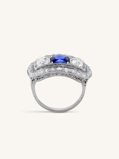 This antique Art Deco sapphire and diamond ring is a true showstopper that captures the opulence of the Art Deco era. At the center of this exquisite ring is a 2.15 carat old mine cushion cut sapphire, radiating with a rich and deeply saturated blue hue. This remarkable gemstone is flanked by two magnificent old mine cushion cut diamonds, totaling approximately 1.70 carats. These diamonds possess a unique charm, with their larger facets that exude a mesmerizing play of light and fire. The beauty Vintage Gia Certified Sapphire Ring, Timeless Sapphire Diamond Ring With Rose Cut, Timeless Sapphire Diamond Ring With Rose Cut Diamonds, Vintage Gia Certified Diamond Sapphire Ring, Vintage Gia Certified Sapphire Diamond Ring, Gia Certified Vintage Diamond Sapphire Ring, Antique Sapphire Ring In Platinum, Sapphire Platinum Diamond Ring Cushion Cut, Platinum Sapphire Cushion Cut Diamond Ring