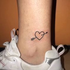 a small heart with an arrow tattoo on the ankle