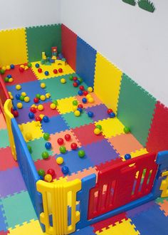 a child's play area with colorful foam tiles and balls on the floor,