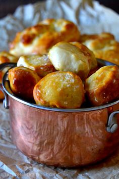 a copper pot filled with baked goods on top of wax paper