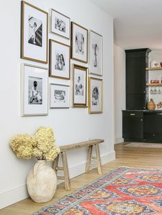 a room with pictures on the wall and a bench in front of it next to a rug