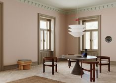 a dining room with pink walls and wooden furniture in the center, along with large windows