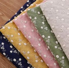 six different colors of fabric with flowers on them, sitting on a wooden table next to each other