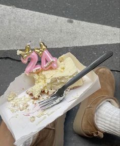 someone holding a piece of cake with the number twenty five on it and a fork