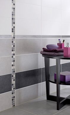 a round table with purple towels and soaps on it in front of a tiled wall