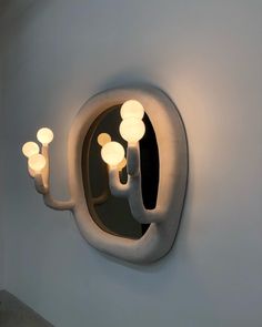 a wall mounted light fixture with three lights on it's side and a mirror in the middle