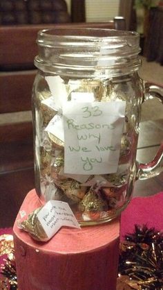 a jar filled with lots of candy sitting on top of a wooden block next to a pile of tinsel