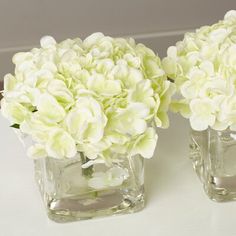 two clear vases with white flowers in them