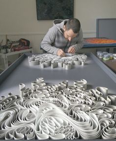 a woman is working on an intricate paper sculpture